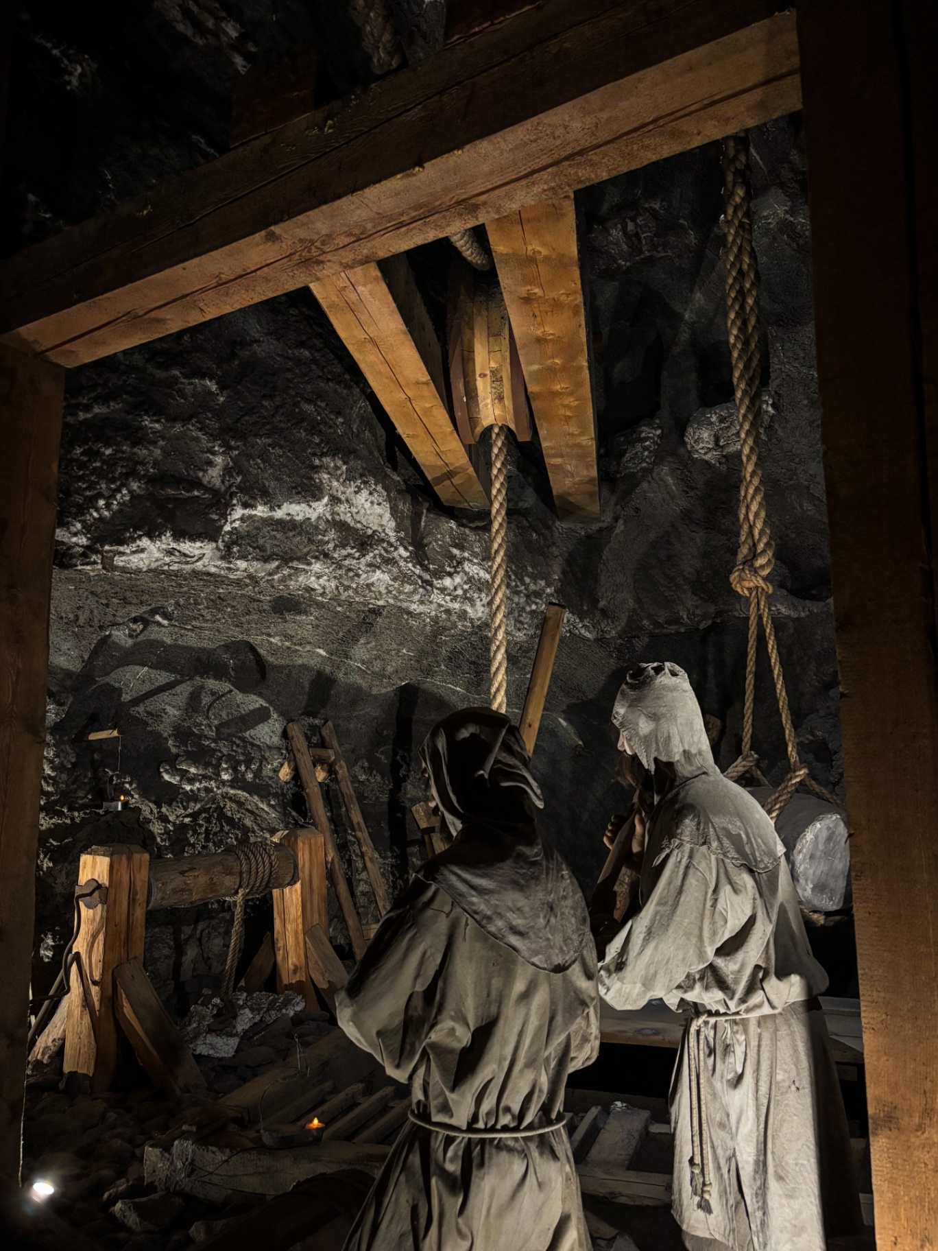 Statues de mineurs actionnant un treuil à corde dans une galerie sombre