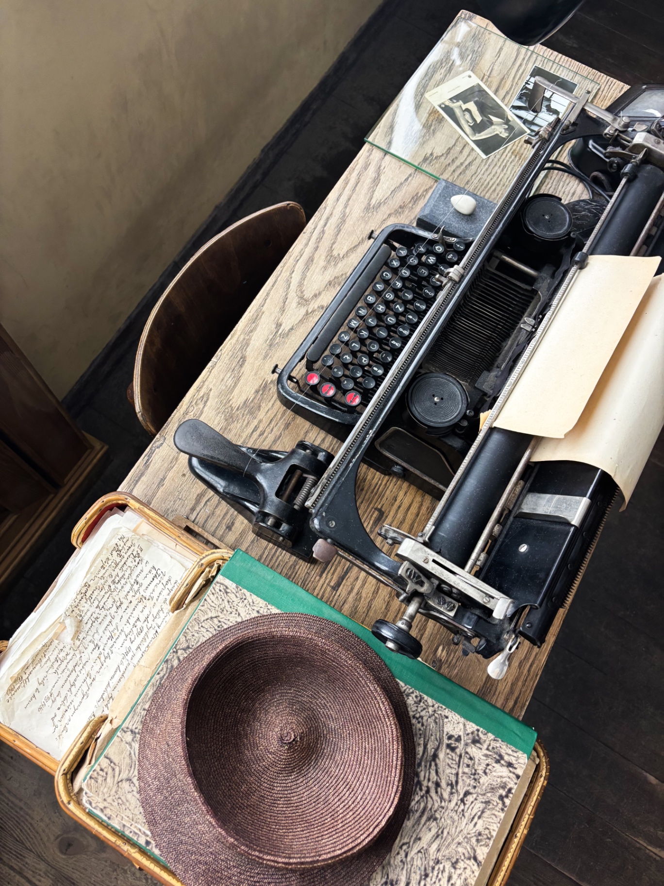 Machine à écrire ancienne posée sur un bureau en bois, avec chapeau de paille et documents d'époque
