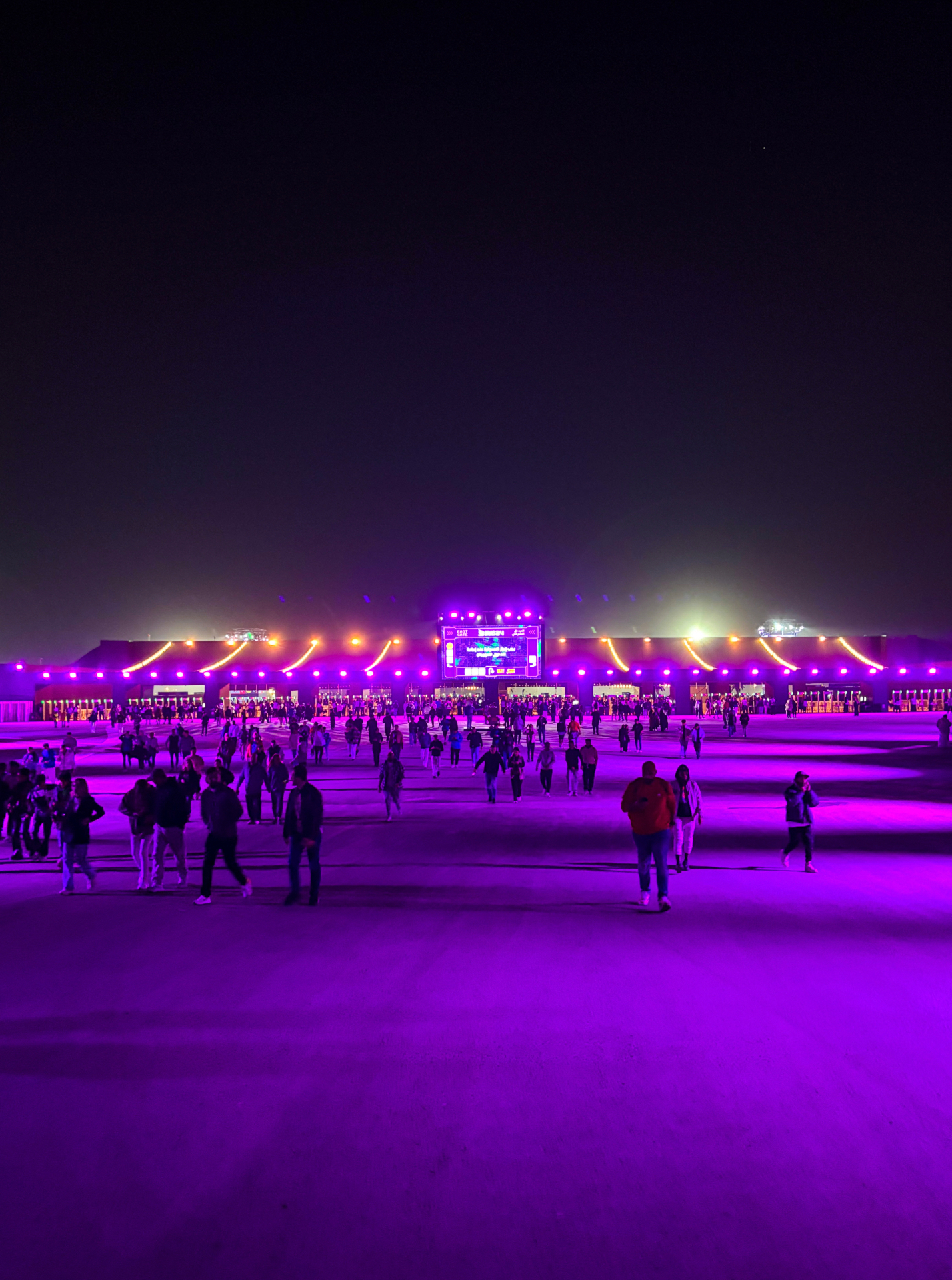 L'entrée du festival Soundstorm illuminée en violet, avec les festivaliers qui convergent vers les contrôles