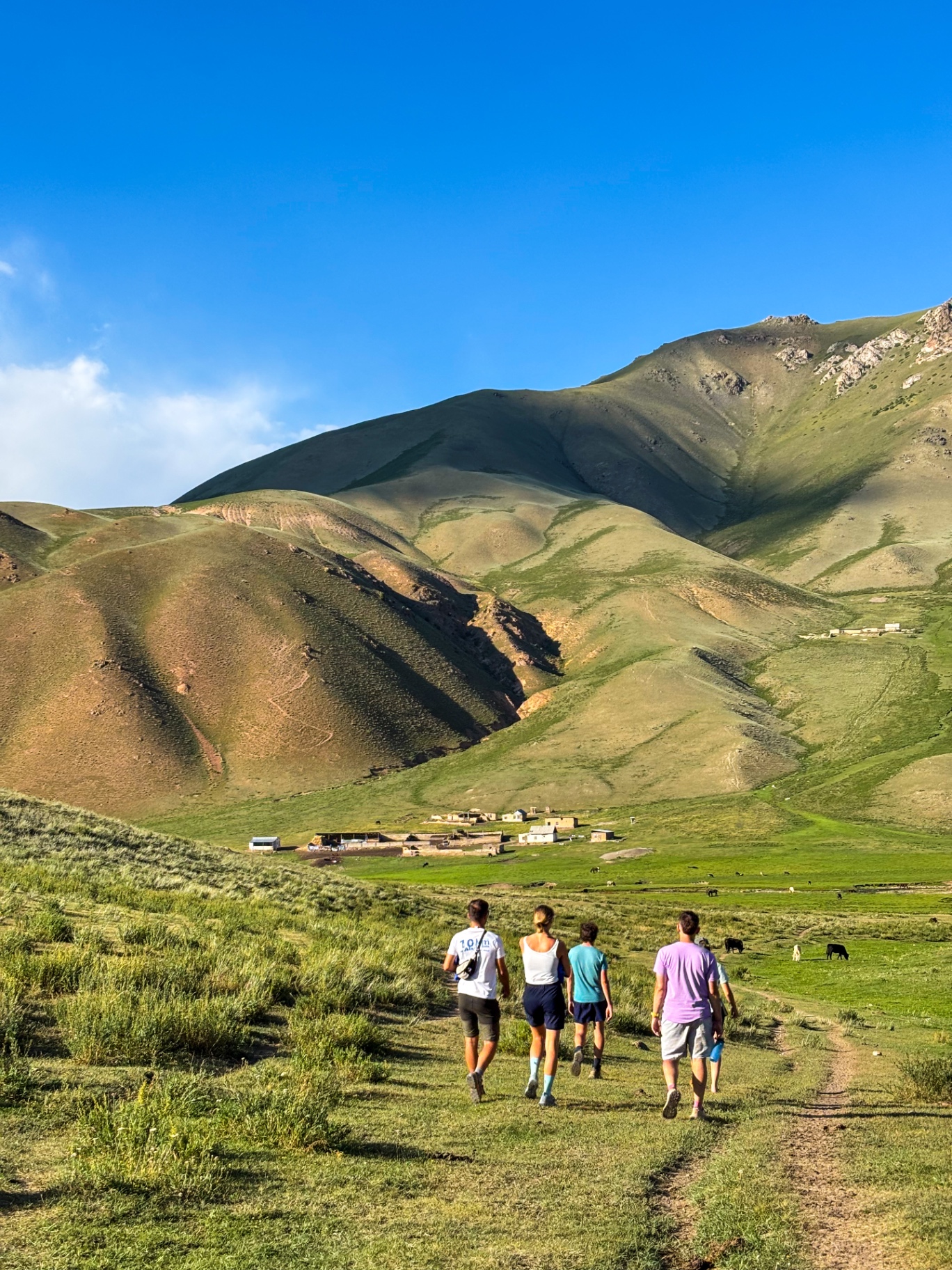 Groupe descendant à pied vers un hameau au creux des collines