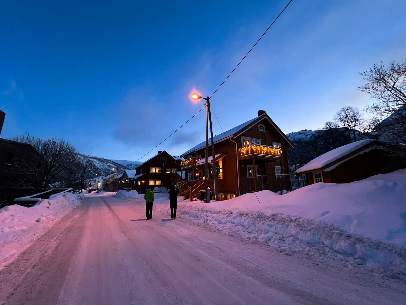 Promeneurs dans une rue enneigée de Tromsdalen bordée de maisons en bois colorées