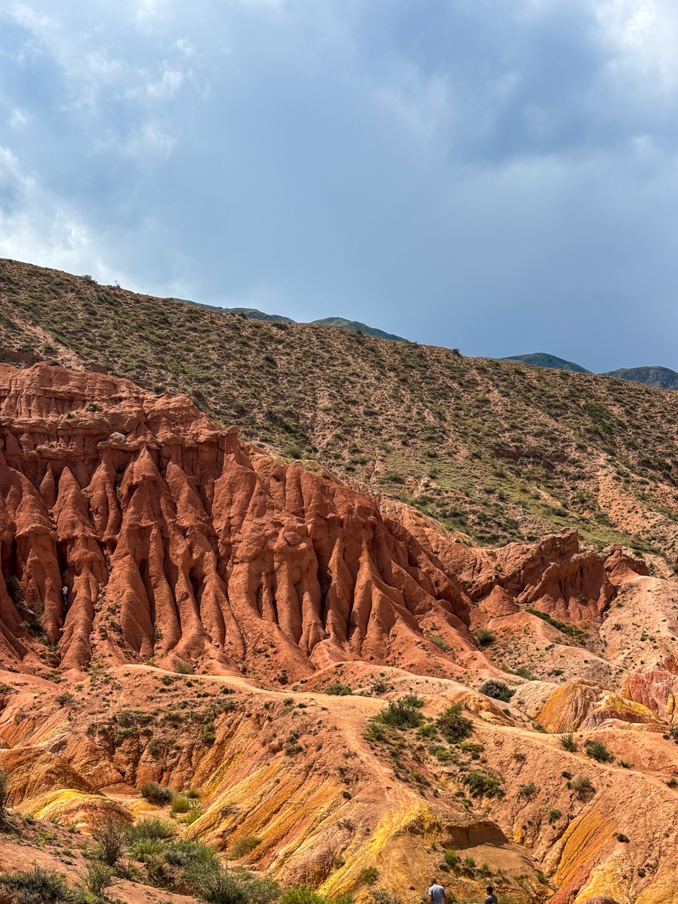 Formations rocheuses rouges effilées adossées à une colline verte