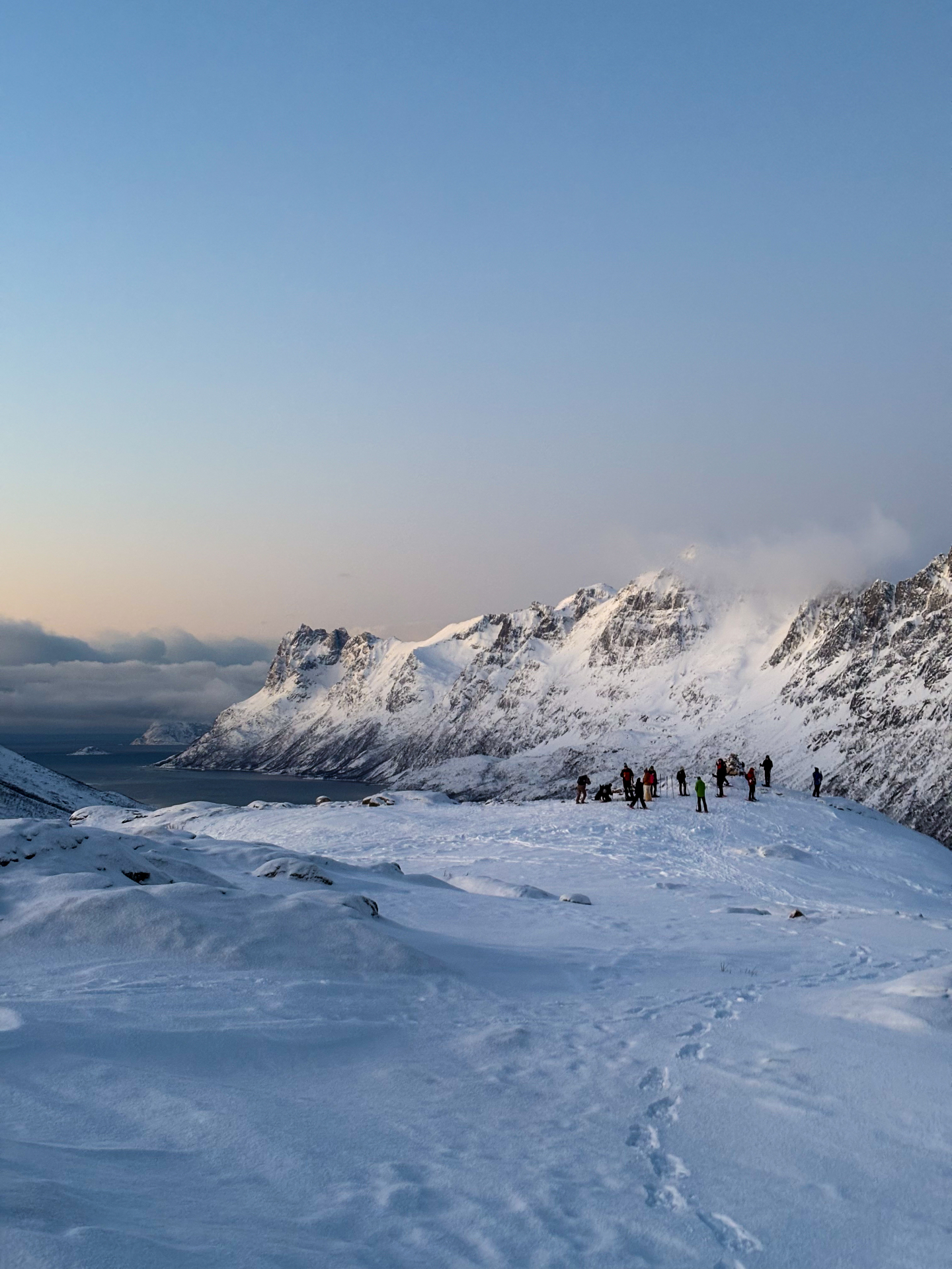 Groupe de randonneurs sur une crête enneigée dominant le fjord de Kvaløya