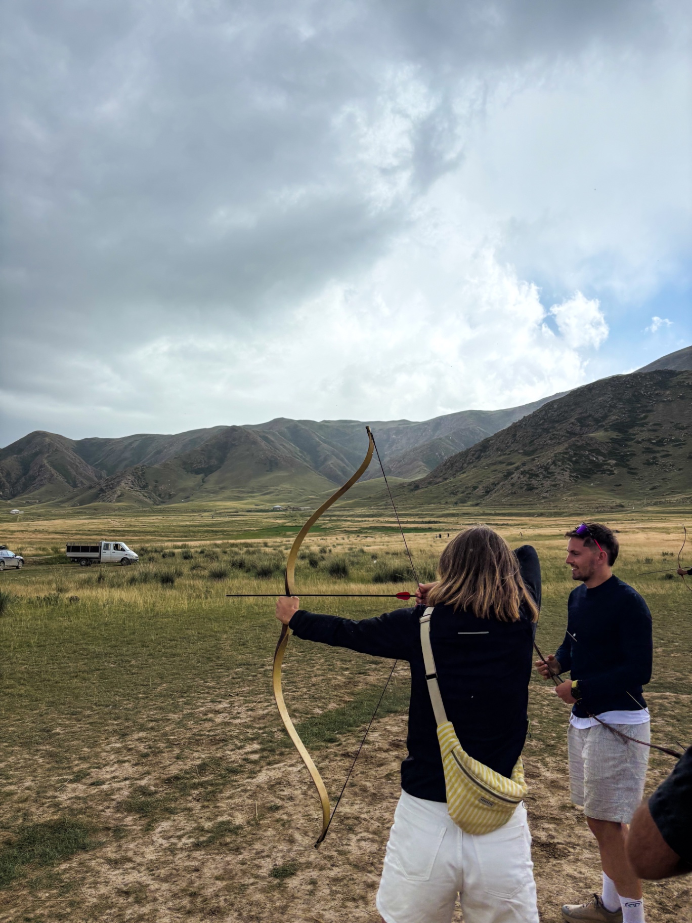 Voyageuse tirant à l’arc traditionnel face aux montagnes