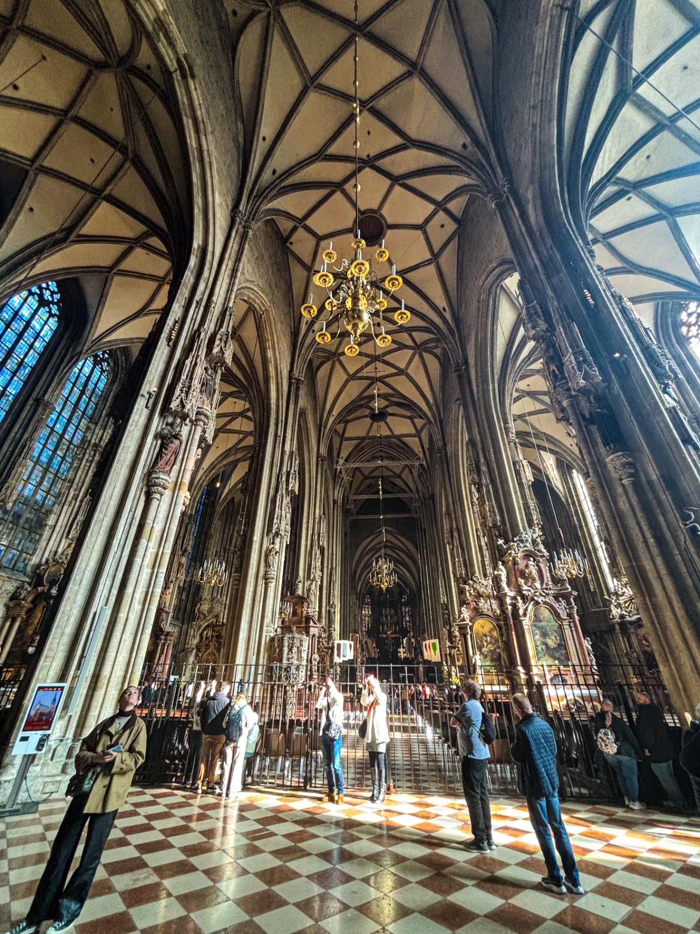 Nef gothique de la cathédrale Saint-Étienne avec ses hautes voûtes, ses lustres dorés et le dallage en damier
