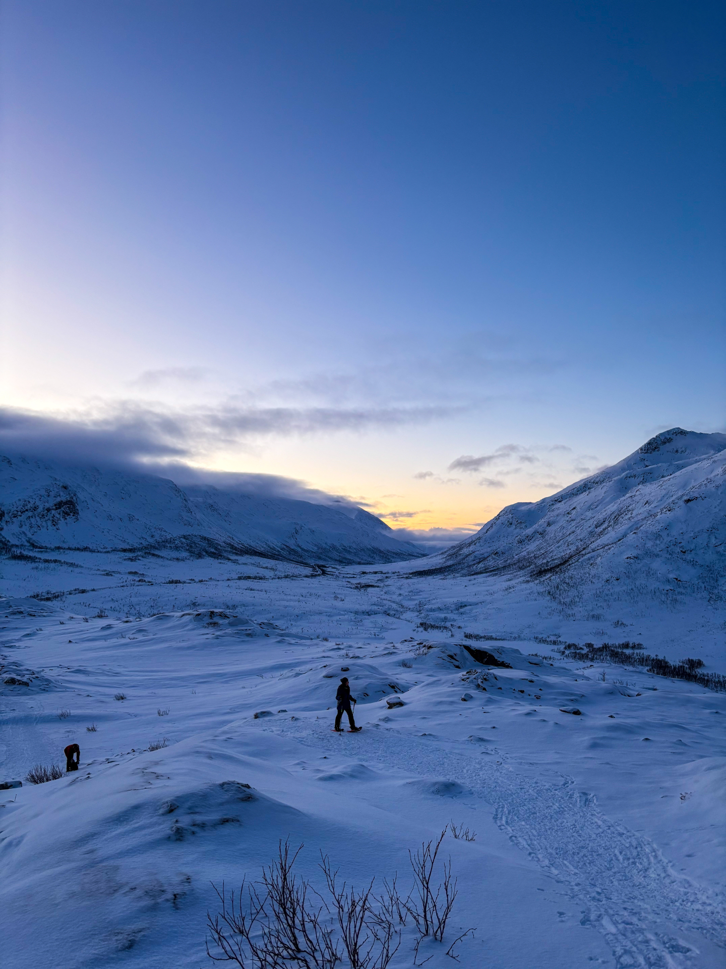 Randonneur en raquettes dans une vallée enneigée de Kvaløya à l’heure bleue