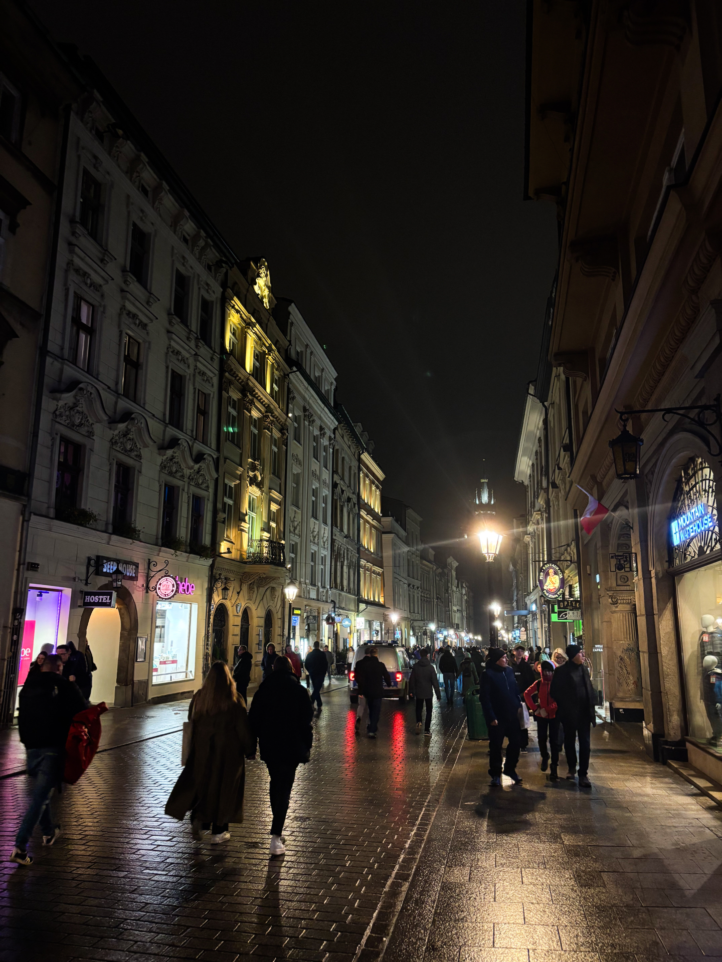Rue animée de Cracovie la nuit entre façades historiques et lampadaires