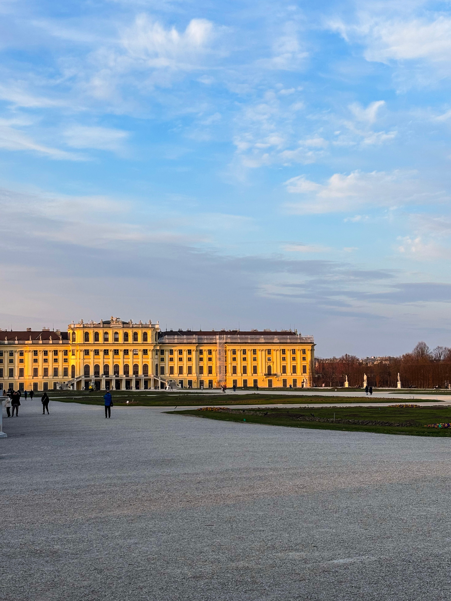 Façade jaune du château de Schönbrunn baignée par la lumière du coucher de soleil