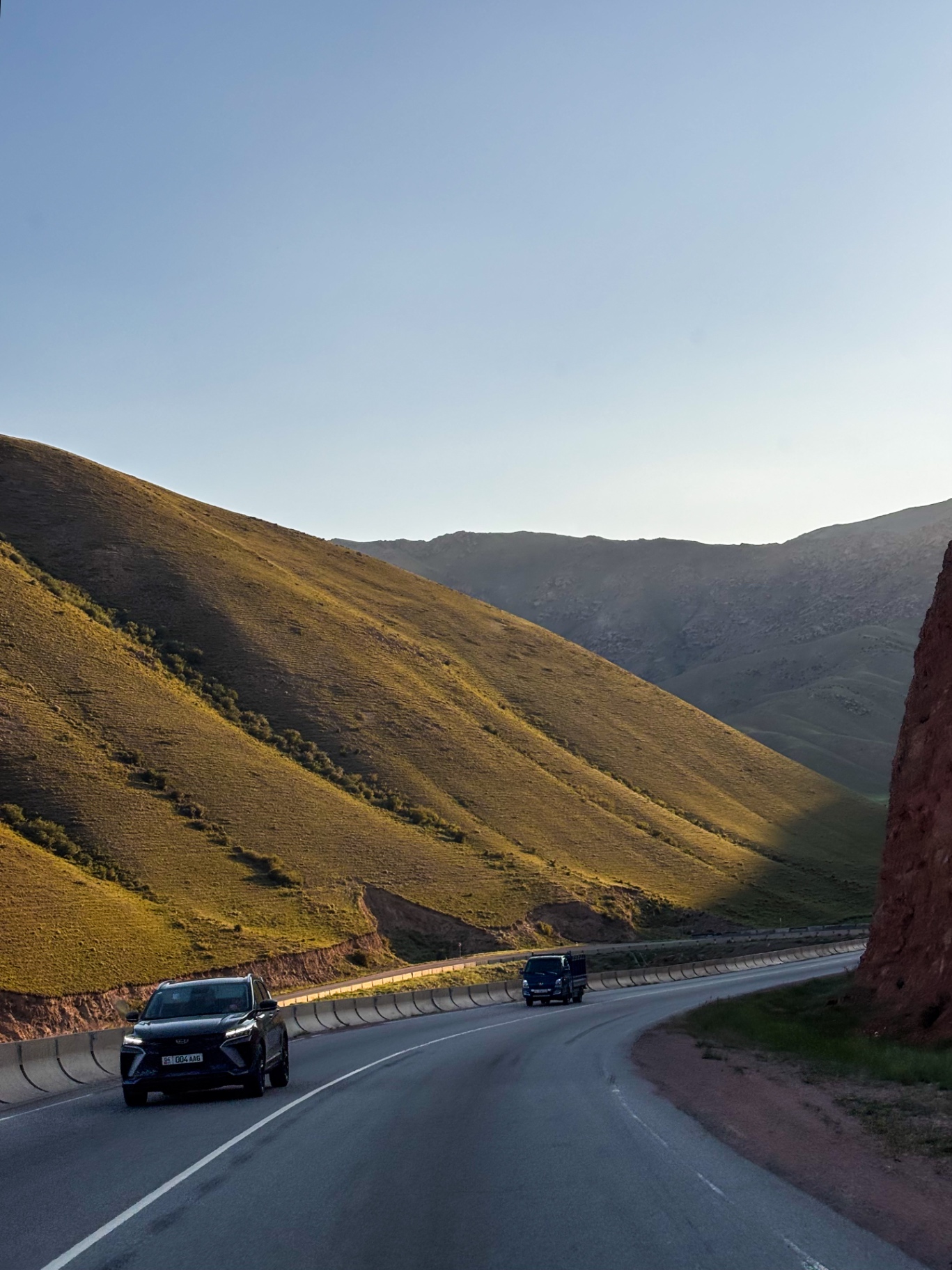 Route serpentant entre des collines dorées par la lumière rasante