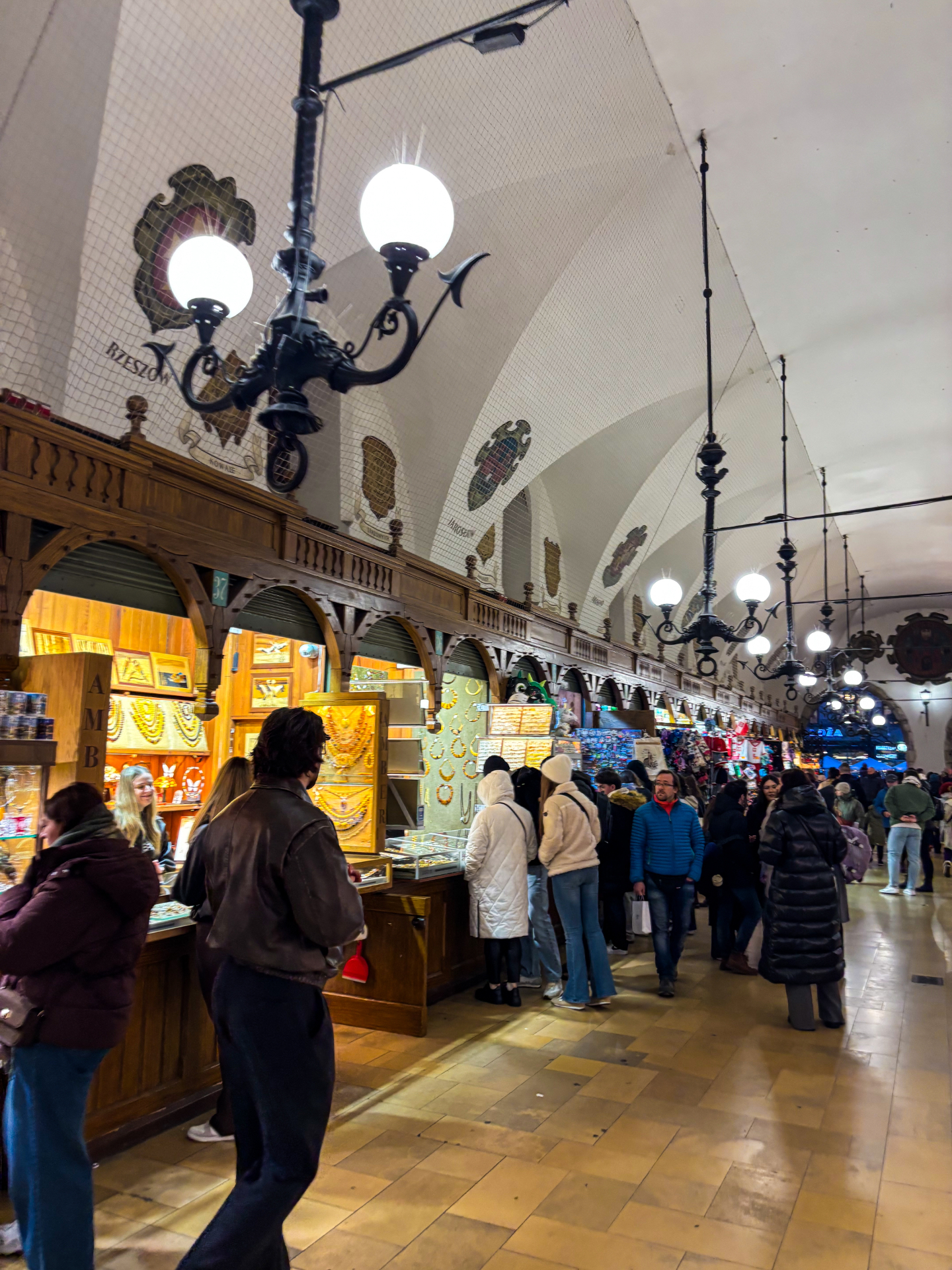 Étals de souvenirs et d'ambre sous les lustres de la Halle aux Draps