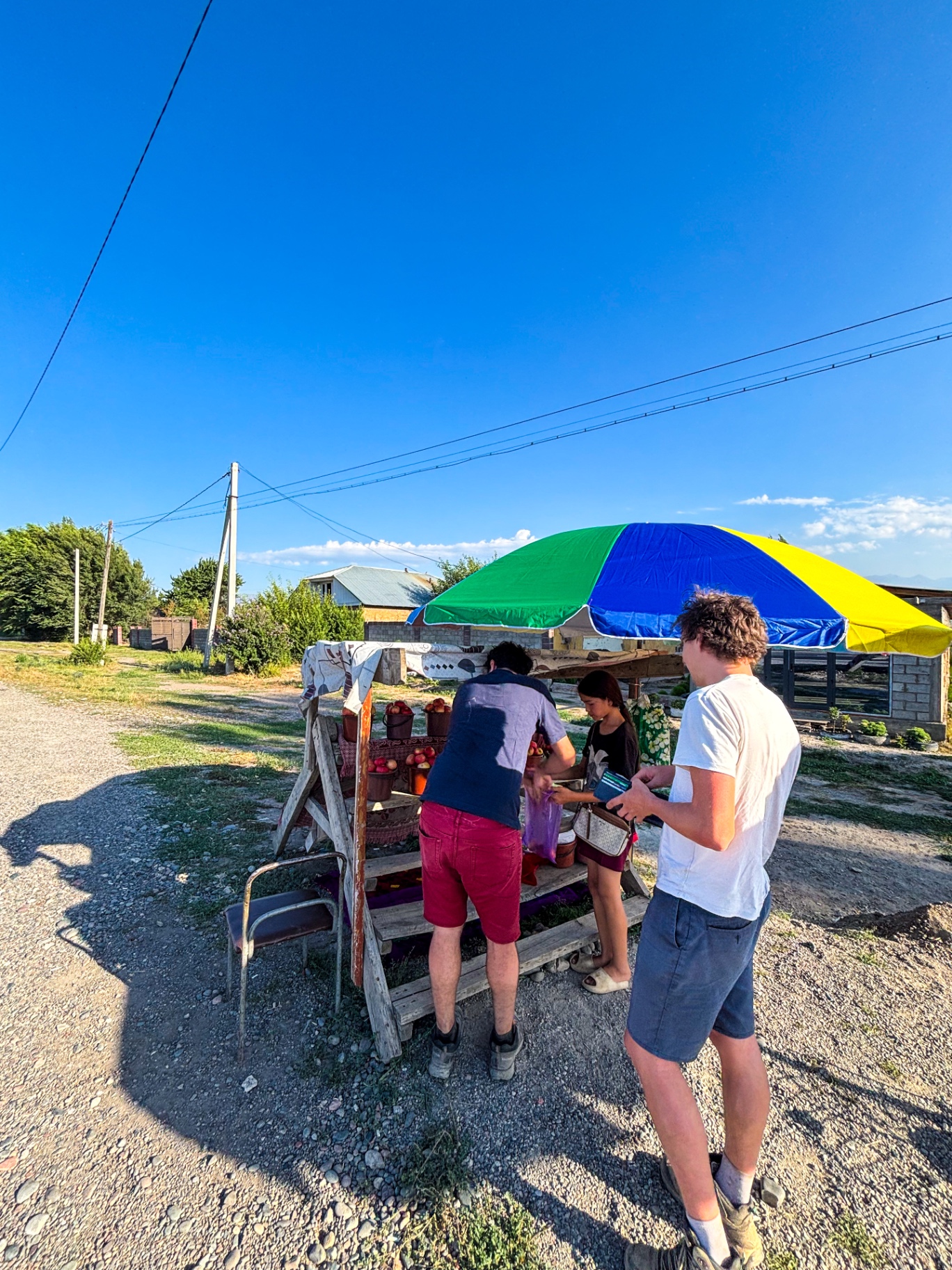 Stand de pommes au bord de la route sous un parasol coloré