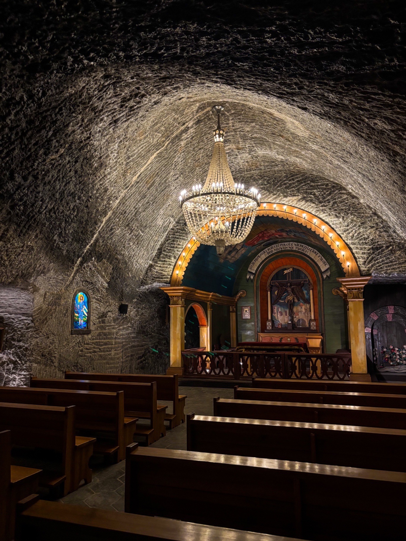 Intérieur d'une chapelle souterraine avec ses bancs de bois et un lustre de cristaux de sel