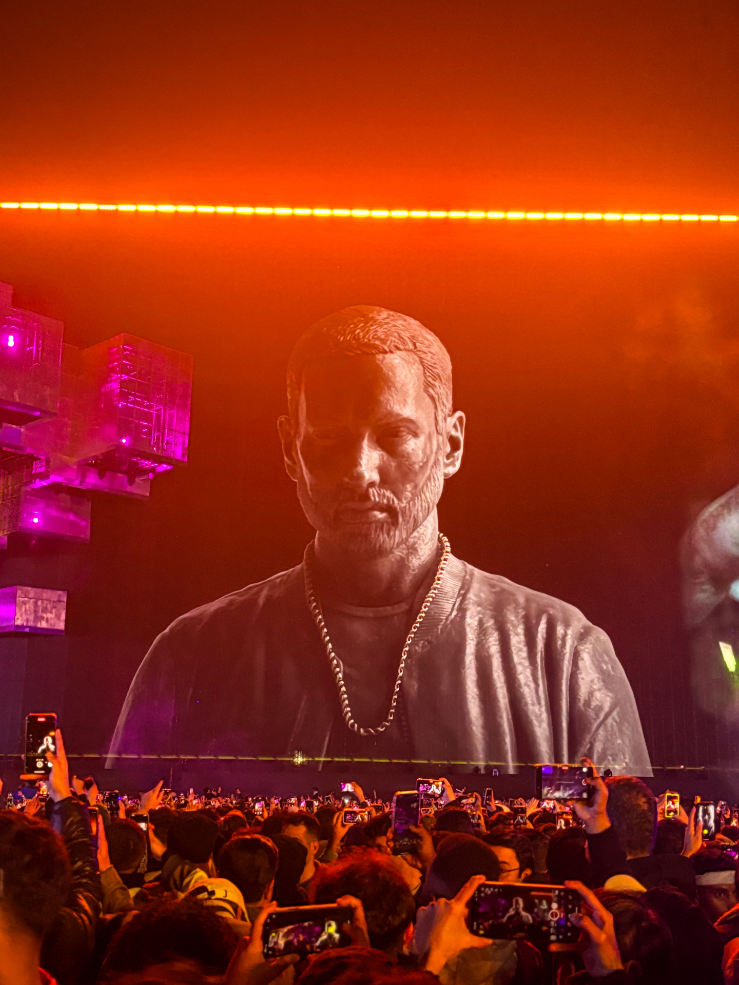 Eminem projeté en immense sur les écrans géants de la scène Big Beast, sous un ciel orangé, au-dessus de la foule