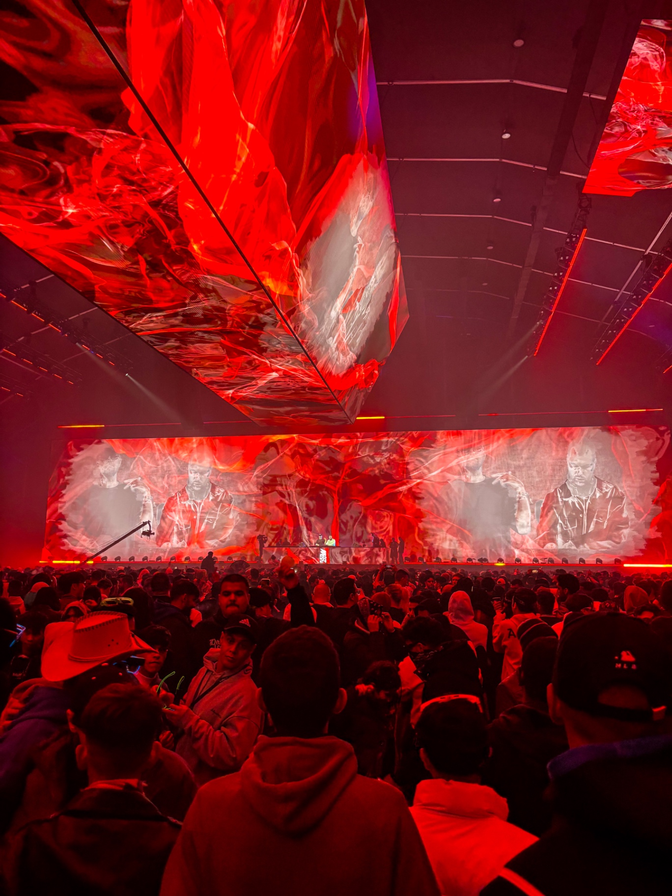 L'intérieur de la Dance Tent plongé dans une lumière rouge, écrans géants au-dessus de la foule