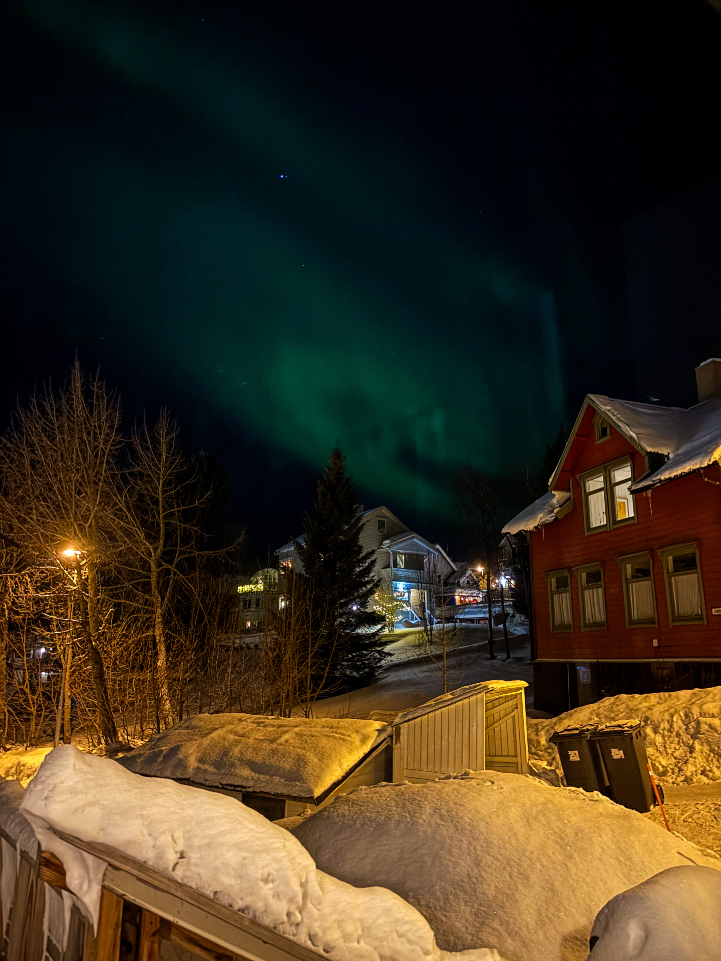 Aurore boréale visible depuis une terrasse enneigée à Tromsø
