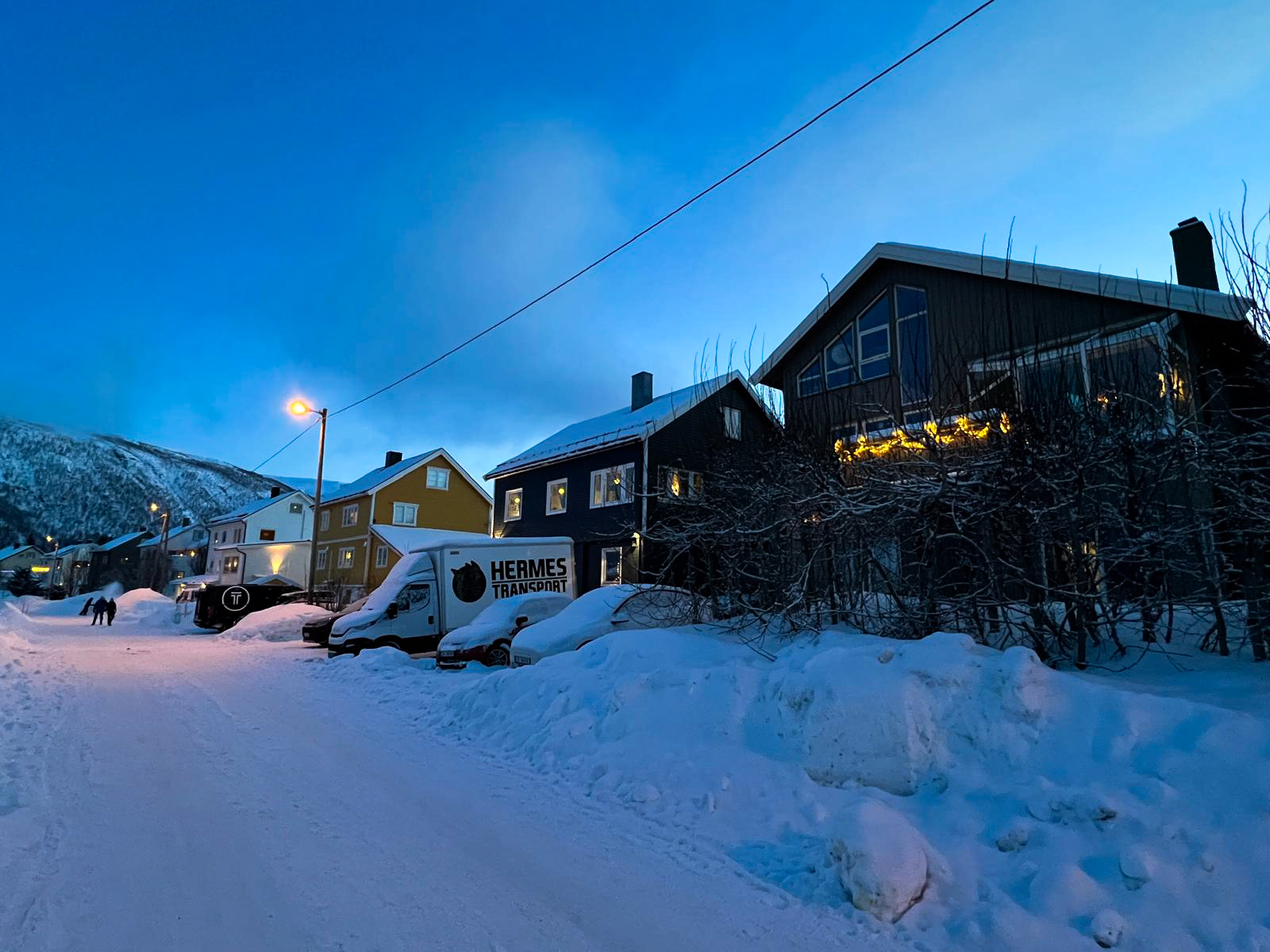 Maisons colorées de Tromsdalen au crépuscule, avec un van Hermes sous la neige
