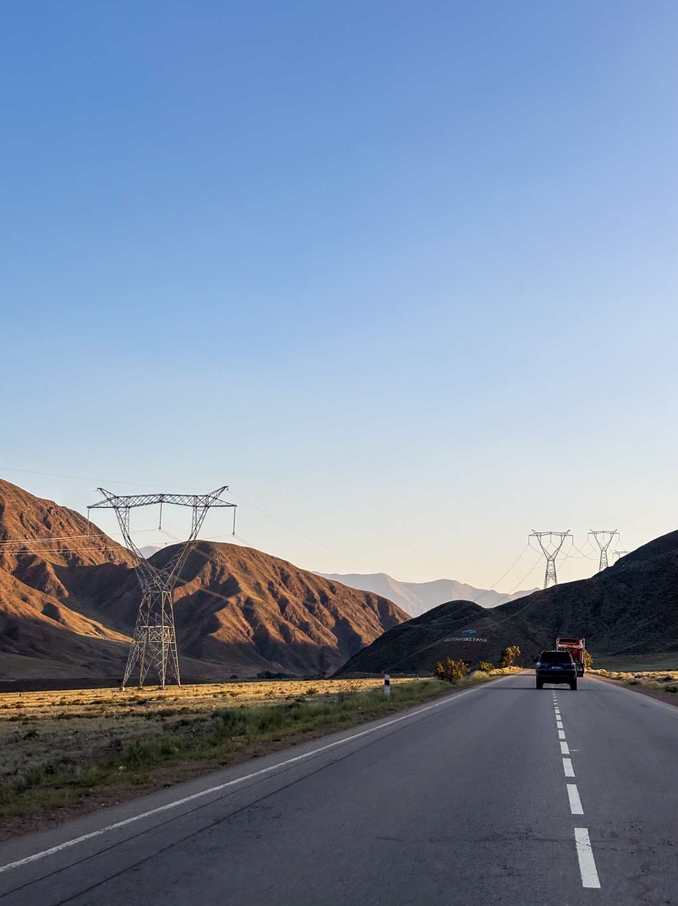 Ligne haute tension traversant une vallée au coucher du soleil