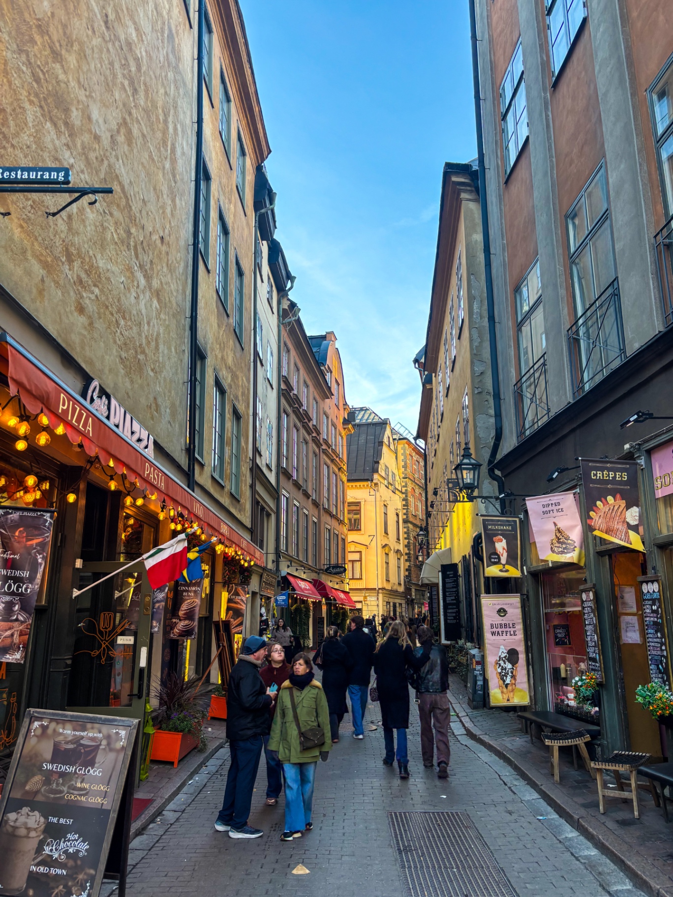 Ruelle pavée animée de Gamla Stan entre façades colorées et enseignes de restaurants