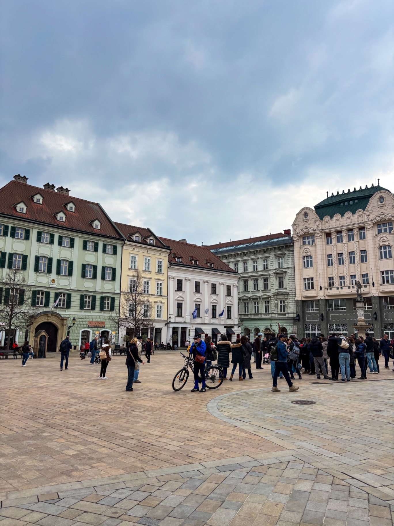 Hlavné námestie, passants et cycliste devant les façades baroques