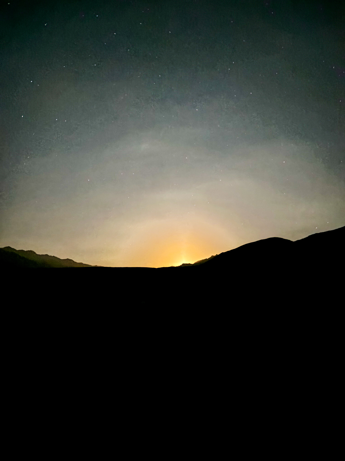 Ciel étoilé et lueur dorée du lever de lune derrière les crêtes