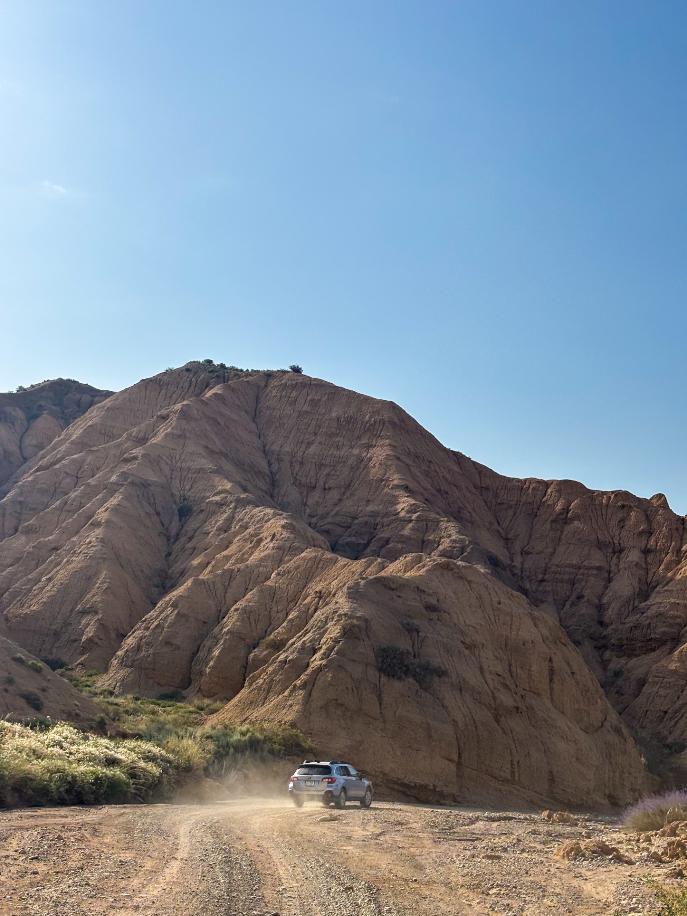 Voiture au pied d’une immense paroi érodée du canyon d’Ak-Sai