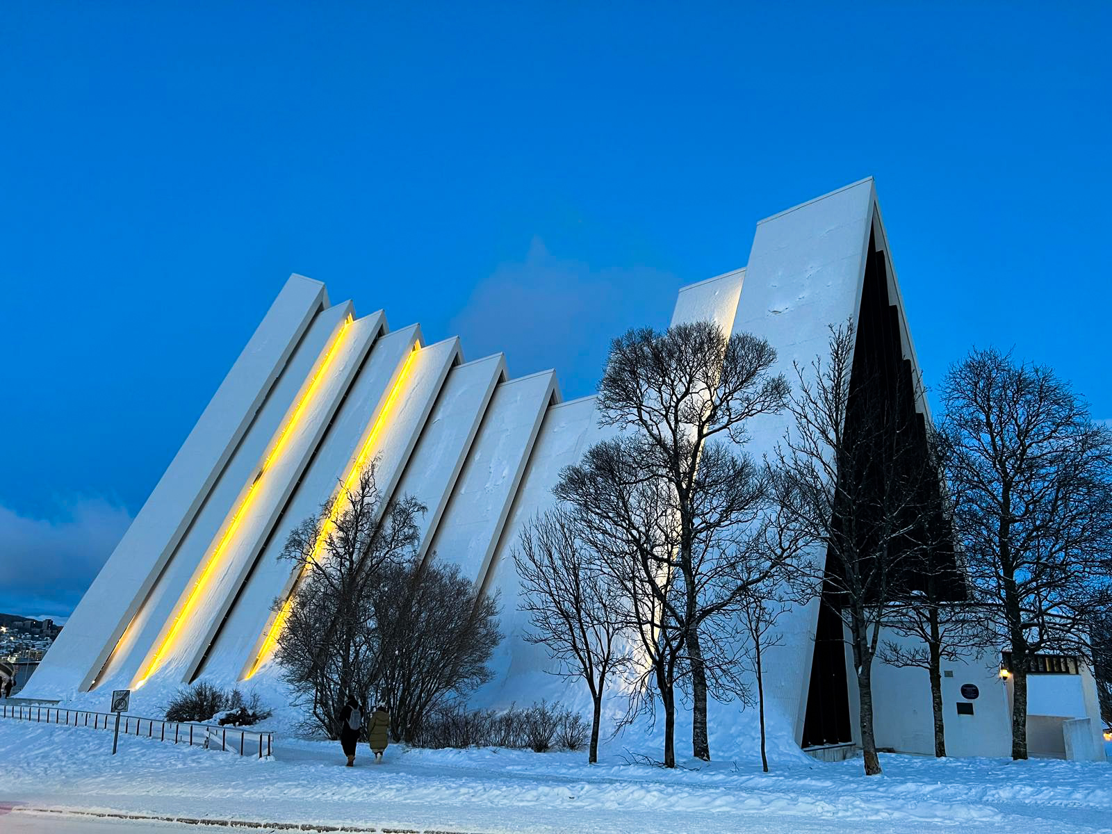 Cathédrale arctique de Tromsø vue de côté, avec ses pans blancs et ses éclairages dorés
