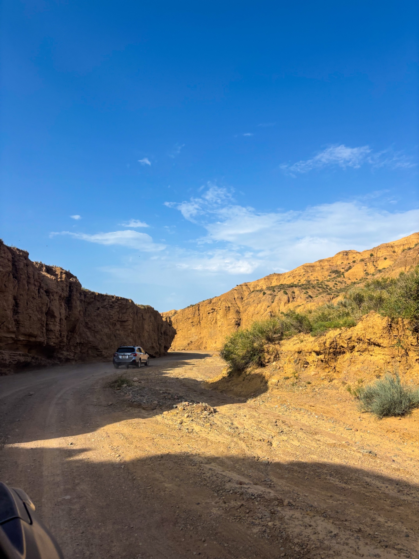 Voiture engagée sur une piste entre deux parois de terre ocre